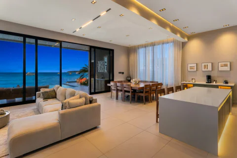 Open-plan living and dining room facing the sea at dusk