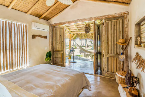 Rustic beach cabana bedroom opening onto a palm-shaded terrace