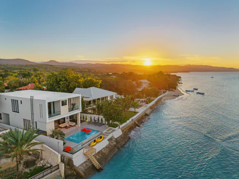 Aerial view of a beachfront villa and pool at sunset